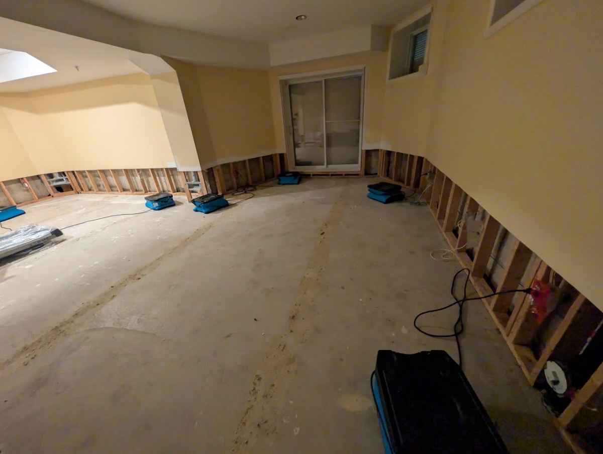 Drying equipment running along basement walls with the wet drywall cut out
